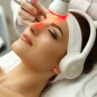 woman-lays-with-towel-closed-eyes-getting-face-treatment-skin-mask-massage-beauty-salon